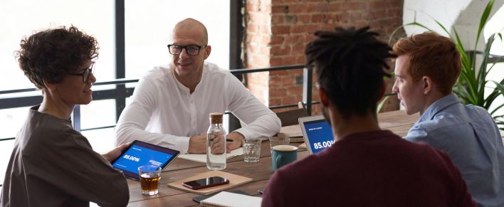 Diverse team collaborating in a modern office setting with laptops and notes on the table.